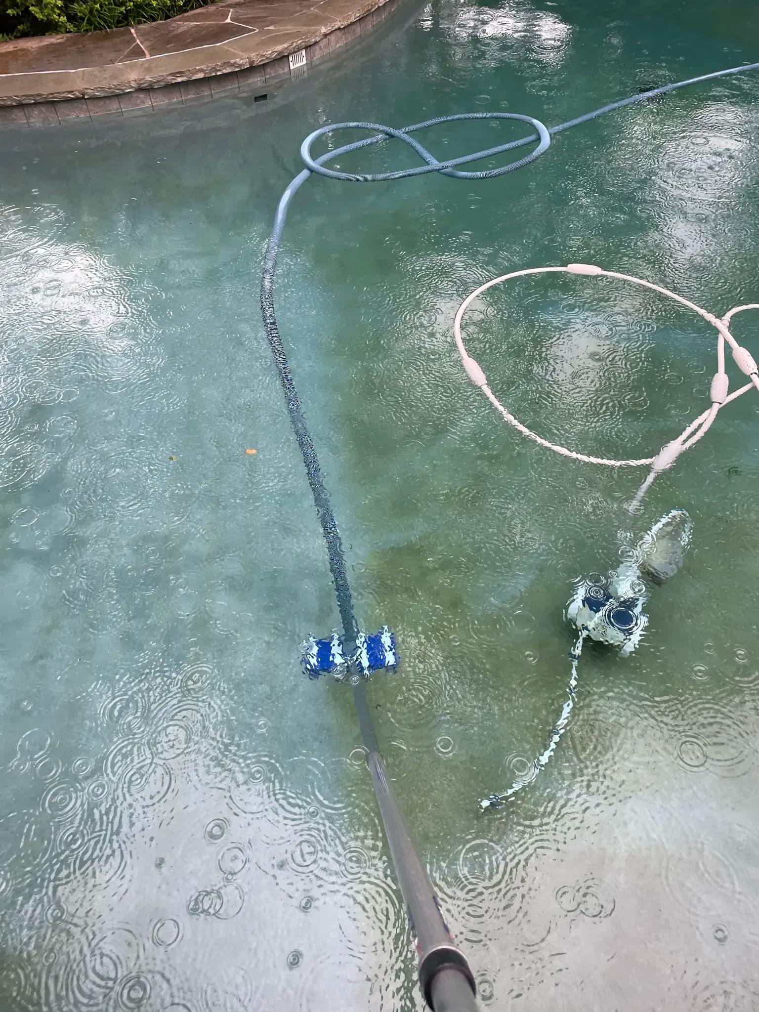 Pool technician vacuuming pool even in the rain